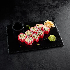 California roll with tobiko and crab, served on a black slate with soy sauce and wasabi