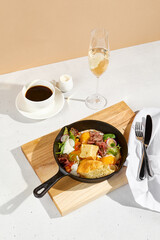 Sunny-side-up eggs in a skillet with roast beef, vegetables, and ciabatta, Americano coffee, and a...