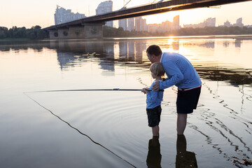 Dad and son relax together, fishing with a fishing rod at sunset. father's day concept. Family fun...
