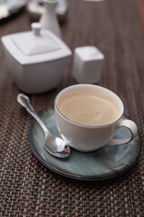 cup of coffee on wooden background. Beautiful foam, greenery ceramic cups, stylish toning,