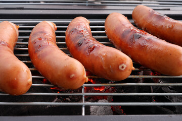 Six sausages on charcoal grill grid close up