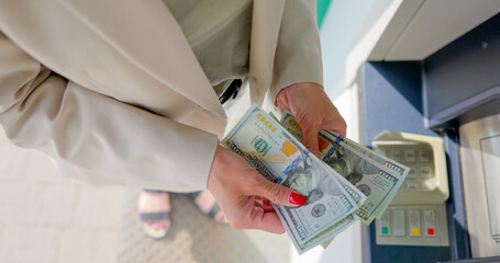 Young woman is counting money at an ATM