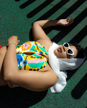 Mujer con gafas de sol y top colorido tumbada al sol