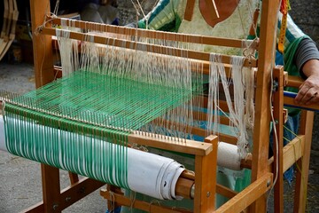 Master weaver is weaving the tapestry with diverse bright threads, close up. Artisanal at work