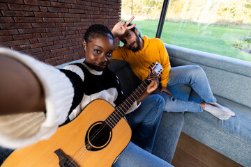 In the photograph, a man and a woman are seated together on a couch with a guitar. They seem to be...