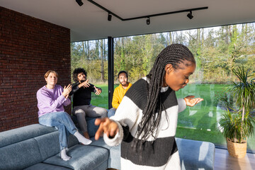 In a living room, a woman is joyfully dancing while a group of people relax on a couch, surrounded...