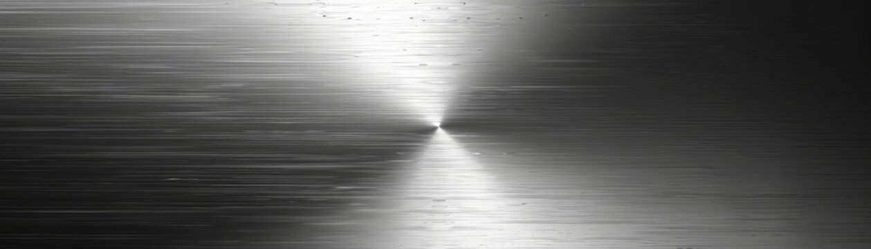 The image is a close up of a shiny metal surface with a radial brushed texture.