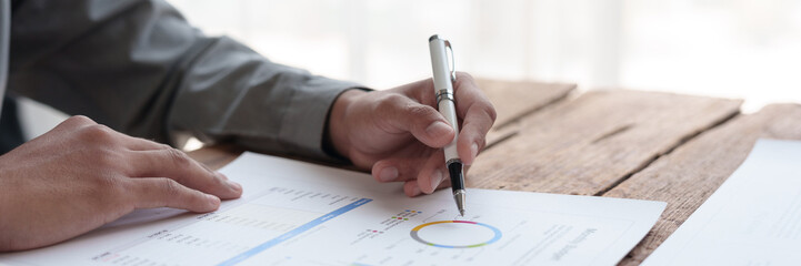 Businessman uses a pen to point at a graph Business income charts in real estate, taxes, management, marketing, technology in private offices.