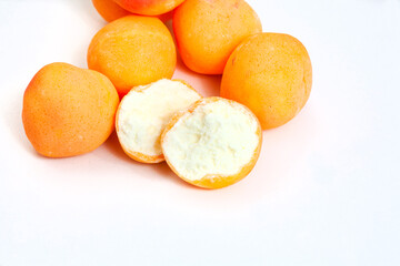  Apricots, retro old-fashioned candy. Apricot sweets with one open sweet showing the spongy inside. Isolated on white with copy space. Apricot mallow candy