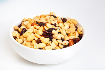 Peanut and raisin mix in round white bowl, isolated on white