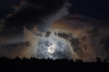 Księżyc w pełni w otoczeniu bujnych kolorowych chmur 
