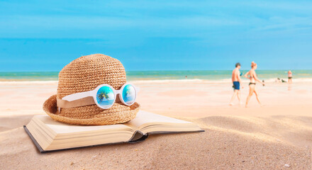 Hat and books placed on the beach. Beach activities. traveling at summer destination.