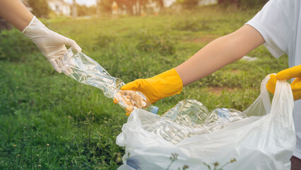 Volunteer boys and his mother help and picking up plastic bottle waste at public parks for recycling, Reuse, and waste management concepts.