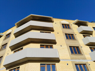 Facade of new multi-story residential building. Sale and rental apartments. Housing development. Cityscape. City life. Real estate. Blue sky. Mortgage concept. Condos. Interest Rate Increase. Flat.