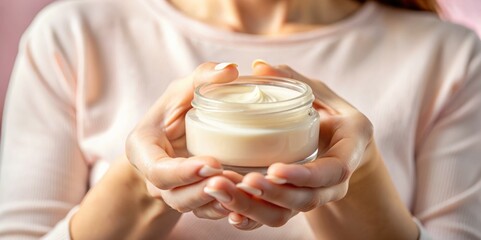Hands of a beautiful well-groomed woman with a cream jar on a pink textural background. Moisturizer for clean and soft skin in the winter. I love the body. Healthcare concept.