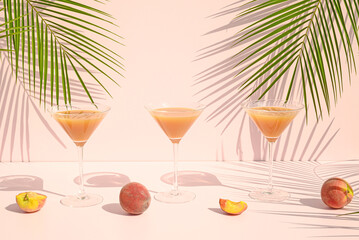 Peach juice and fruit with palm leaves on a pink background. Summer refresing drink concept.