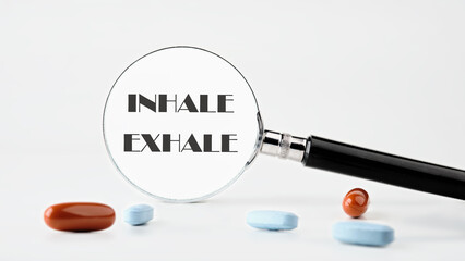 INHALE EXHALE written words through a magnifying glass on a light background. Concept photo