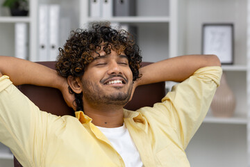 Man relaxing at his desk with eyes closed and a smile