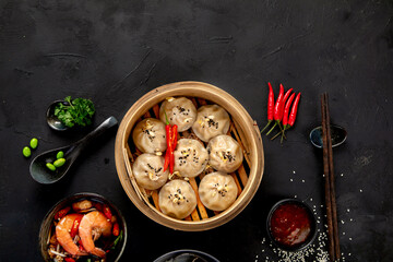 Chinese hot food. Dumplings, soy sauce, shrimp on black background. Traditional asian lunch