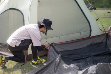 キャンプでテント設営をする人　フライシート