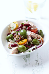 Salad with tuna, green olives and cherry tomatoes. Bright wooden background. Close up. Copy space.
