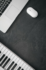 Piano, laptop and computer mouse on a textured black background.