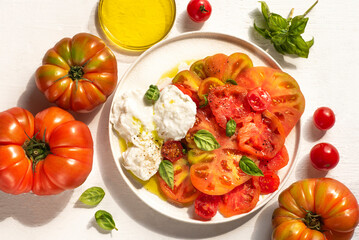  Mozzarella Bufala, Cherry and Ox's Heart tomatoes and basil. Italian Southern Ingredients for summer recipes, Mediterranean diet, farmers  healthy food. White background, sunlight, summer vibes