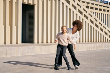 A young girl and an older woman are playing together on a sidewalk