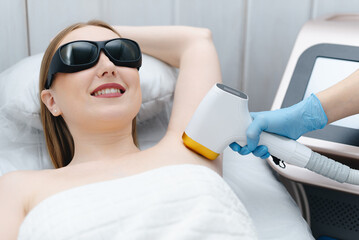 laser epilation, hair removal procedure, young beautiful caucasian smiling woman lying on couch in...