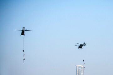 Para commandos slithering and rappelling from helicopter