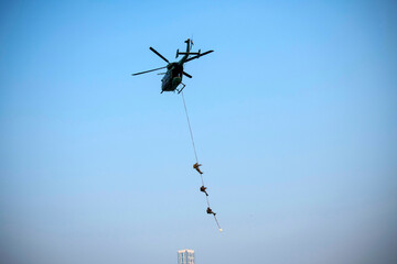 Para commandos slithering and rappelling from helicopter