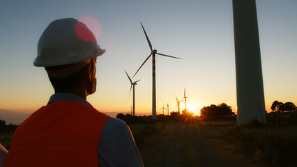 Engineer Staring At The Sunset Behind A Windmill
