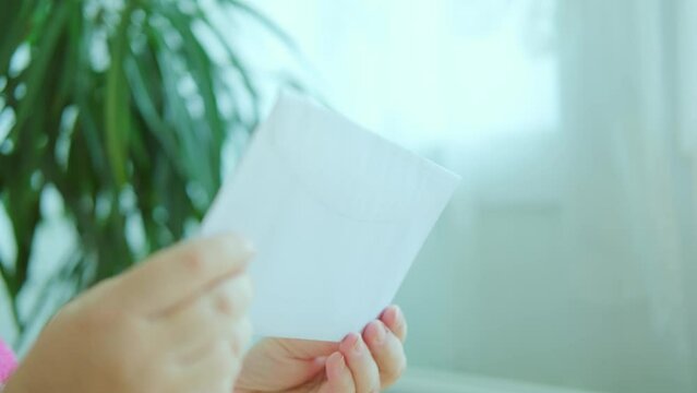 close-up shot of female hand holding white paper envelope, receiving Mail, letter, message concept, important news or personal communication, election day