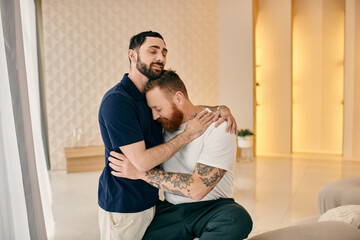 Happy gay couple in casual clothes sharing a warm hug in a modern living room, expressing love and connection.