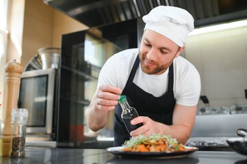 Closeup of a concentrated male chef garnishing food in the kitchen