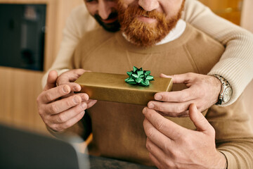 A man with a beard joyfully holds a gift box, expressing love and gratitude in a modern apartment.
