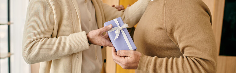 A man joyfully presents a gift to his partner in their modern apartment, expressing love and...