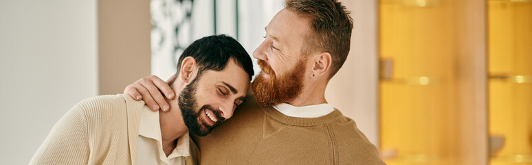 Obraz premium Two men hug each other warmly, expressing love and affection in front of a vibrant yellow wall.