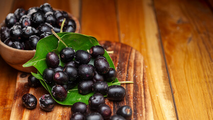 Close-up of 'Indian blackberry' or Jamun (Syzygium cumini) fresh fruits. Isolated on a wooden background. Top view.
