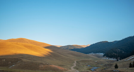 Landscape during autumn. In the foreground, grassland and meandering river bordered by trees with...