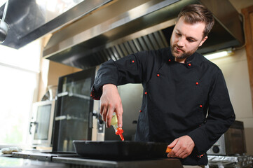 Chef of a Big Restaurant Prepares Dishes. Modern Kitchen is Made of Stainless Steel and Full of Cooking Ingredients