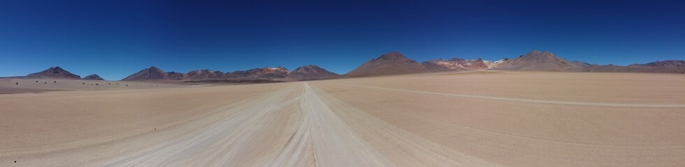 Sandy track toward multi-color mountains on the Altiplano in Bolivia
