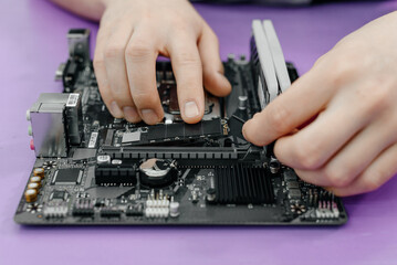 system administrator installing SSD into motherboard, assembling PC of different accessories or...