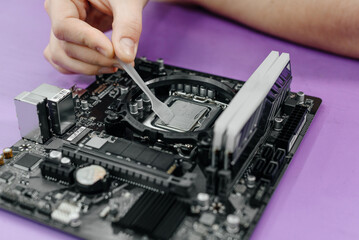 system administrator applying thermal paste to processor for installing into motherboard, assembling PC of different accessories or components, close-up view of hands, computer repair and maintenance