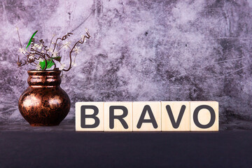 Word BRAVO made with wood building blocks on a gray back ground