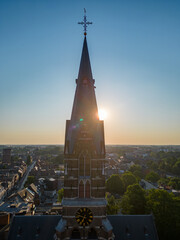 Aerial view of historic church tower at sunset over serene town, creating peaceful, spiritual...