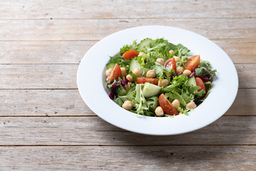 Healthy chickpea salad with tomato,lettuce and cucumber on wooden table. Copy space