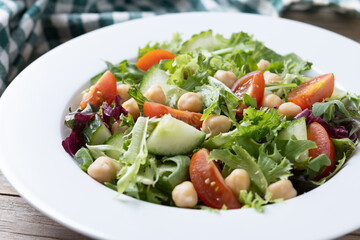 Healthy chickpea salad with tomato,lettuce and cucumber on wooden table. Close up