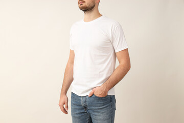 Fototapeta premium A young guy in a white T-shirt on a light background