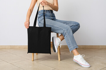 A woman is sitting on a chair with a bag in her hands